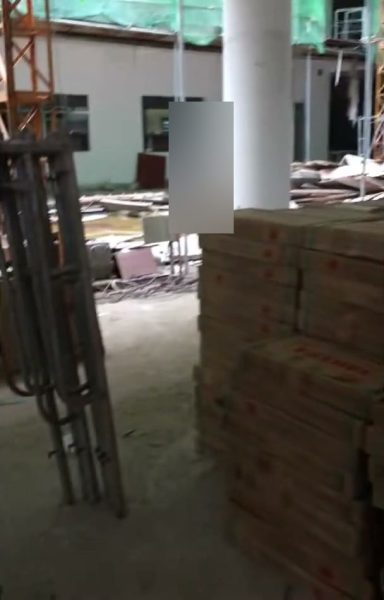 Chồng thùng gạch Taicera cạnh cột trong tầng trệt Trường THCS Ngô Quyền đang thi công, có giàn giáo