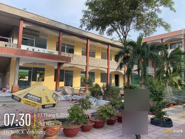 Dãy phòng học 2 tầng sơn vàng, cột đỏ đang hoàn thiện, sân lát gạch ở Trường Tiểu học Vĩnh Hưng