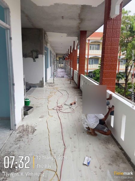 Hành lang dài đã lát gạch, thợ đang làm lan can tại Trường Tiểu học thị trấn Vĩnh Hưng, Tây Ninh